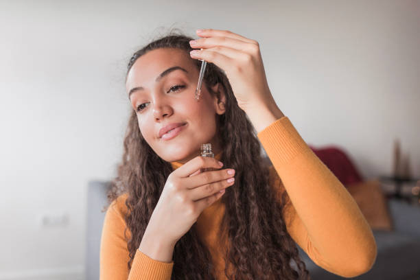 Young satisfied woman using face oil in her daily skin routine stock photo