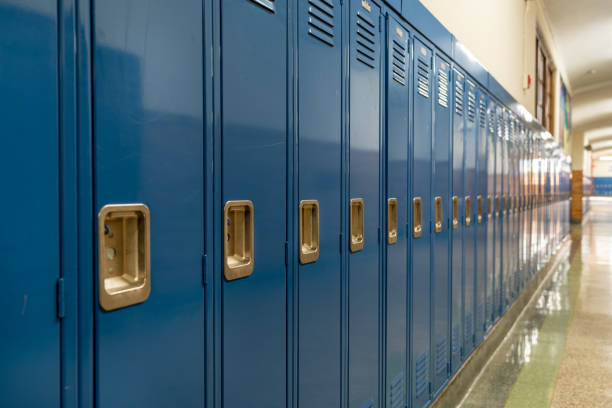foto de un casillero de metal azul a lo largo de un pasillo anodino en una típica escuela secundaria de los estados unidos. no hay información identificable incluida y nadie en el pasillo. - edificio escolar fotografías e imágenes de stock