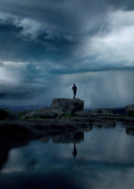 Man stands on a rock by a lake under a dark cloudy sky. 3D render.