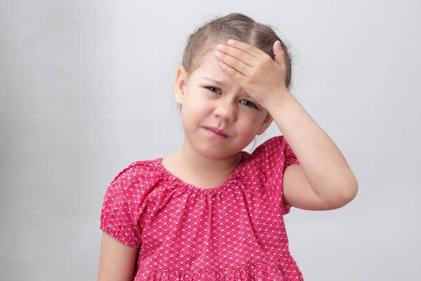 istock Child with headache holding hand on forehead 1439808740