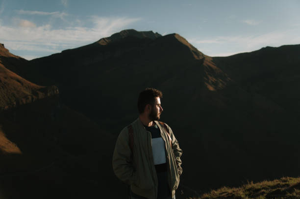 istock Young man by mountains at sunset 1439809167