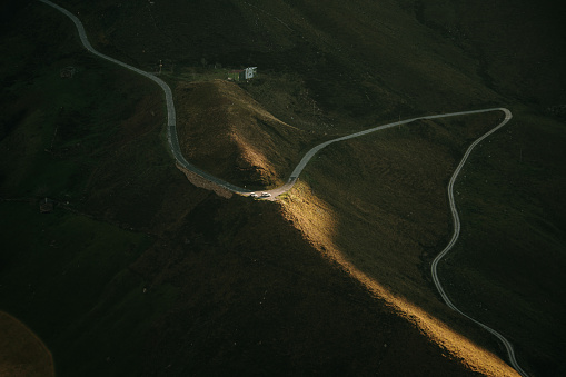 A narrow mountain road as seen from above with sunset light