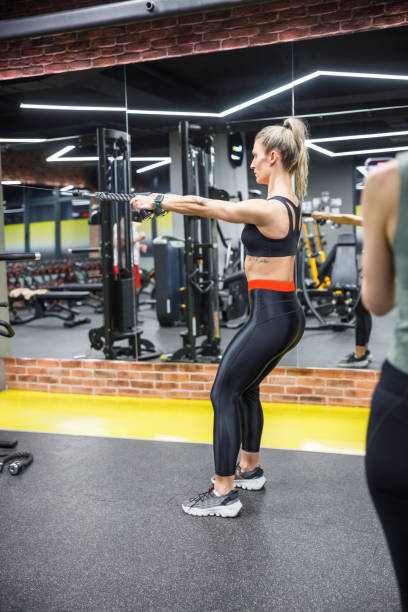 istock Personal trainer showing exercise on lat machine in the gym 1439810082