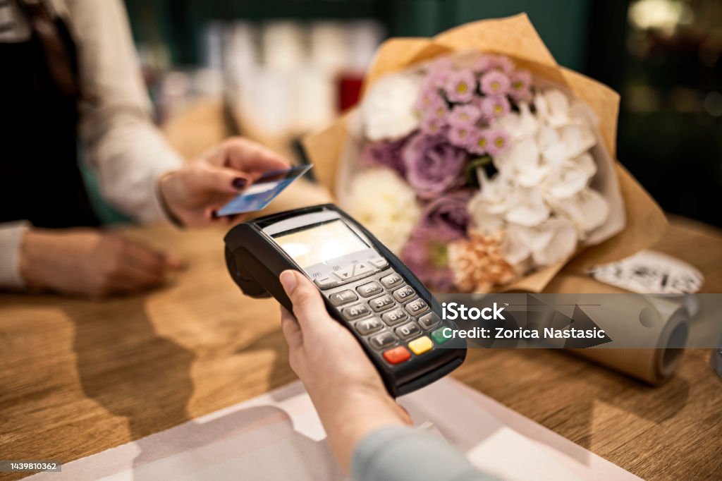 Making payment with credit card at flower shop Cheerful young florist working at flower shop Credit Card Stock Photo