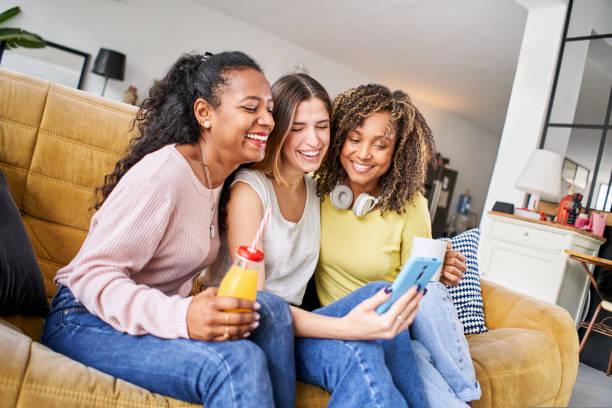 istock Three cheerful Happy smiling women using mobile smart phone looking screen digital device. Shopping online social media network addicted people technology 1439814390