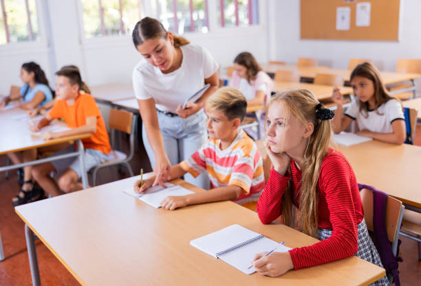 istock Group of preteen schoolchildren diligently making notes in class 1439814814