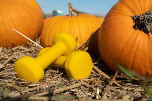 istock Dumbbells and pumpkins on a farm, autumn or fall composition. 1439816127