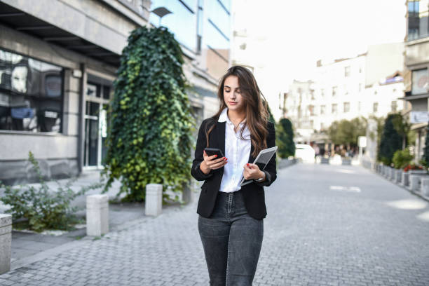 istock Beautiful Businesswoman Checking Work Schedule And Going Towards Office Building 1439816197