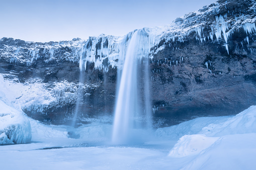 Seljalandsfoss waterfall, Iceland. Icelandic winter landscape.  High waterfall and rocks. Snow and ice. Powerful stream of water from the cliff. A popular place to travel in Iceland.