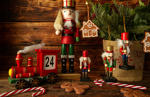 Wooden train Christmas advent calendar. Countdown to Christmas festive decoration. Counting down the days until Christmas wood number blocks. With nutcracker figures, gingerbread man cookies, candy canes and tree branches. Holiday season concept, composition on wooden background.