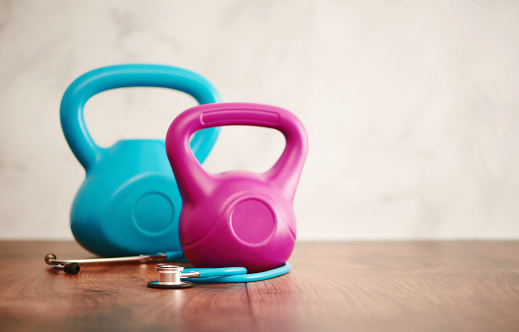 Kettlebells with stethoscope on a wood floor with copy space. Healthy living