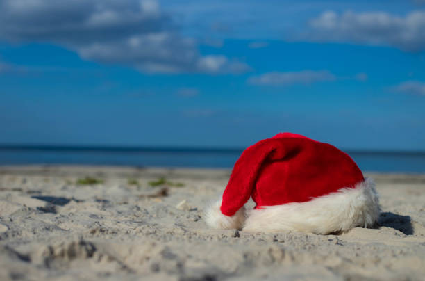istock Santa Claus hat on the sandy beach 1439821346