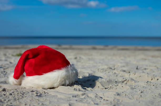istock Santa Claus hat on the sandy beach 1439821350
