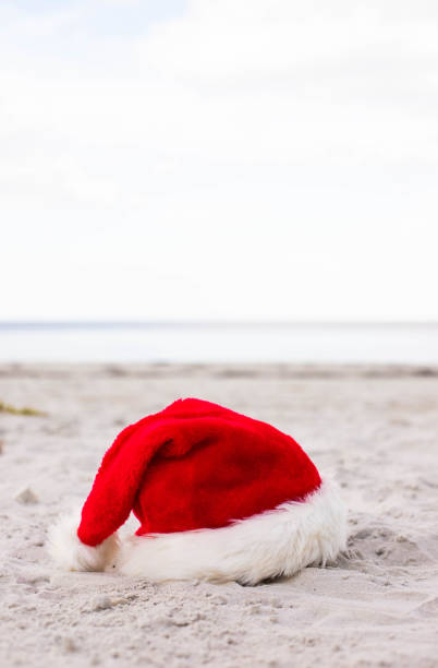 istock Santa Claus hat on the sandy beach 1439821355