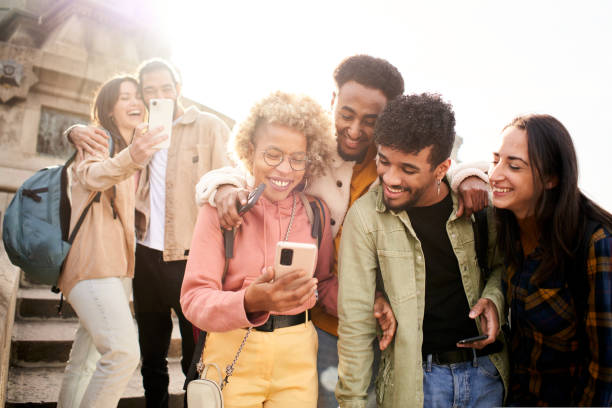 istock Group of cheerful friends watching smartphone outdoors. People using digital device and sharing in social media togethers. 1439824640