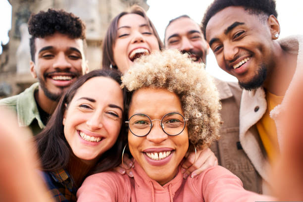 Young multiracial people taking a selfie with smartphone and having fun in the city outdoors. stock photo