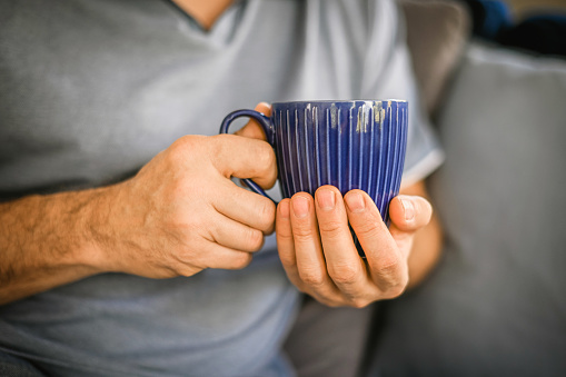man drinking tea from a blue mug