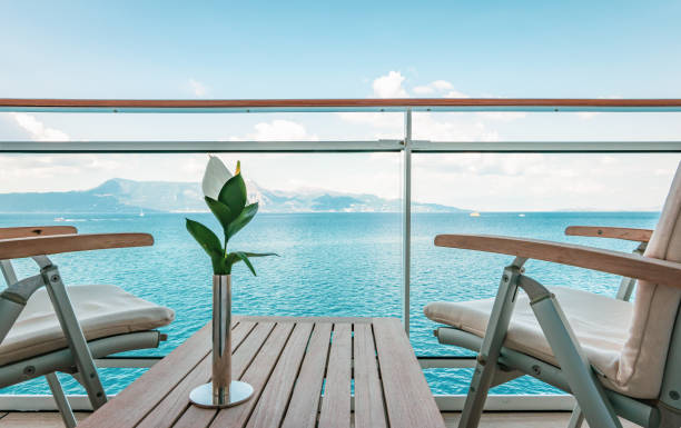 Luxury outdoor furniture on cruise ship balcony. Stylish wooden outdoor table and chairs on balcony of cruise ship. Flower on the table. Sea background. balcony stock pictures, royalty-free photos & images