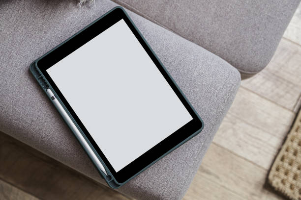 istock Tablet with blank screen and stylus on sofa in living room. Digital technology background 1439826952