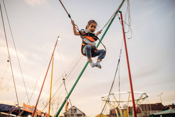 One girl, cute little girl secured in a rope swing fun experience in amusement park.