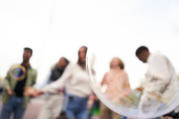 Focus on a soap bubble. Defocus in the background Happy people dancing outdoors. Group of friends having fun in a day party. High quality photo