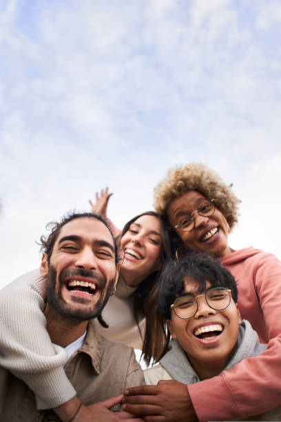 Vertical pic of Group of young people looking at the camera outdoors. Happy smiling friends hugging. Concept of community and youth lifestyle stock photo