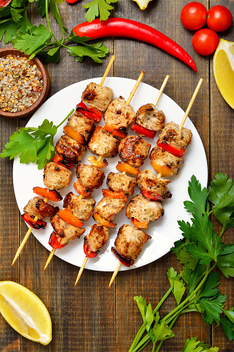 Barbecued chicken kebab on white plate. Top view, flat lay