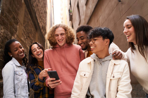 istock Group of happy young teen people using smartphone outdoors while watching something in mobile and laughing. Concept of technology, friendship and community 1439830641