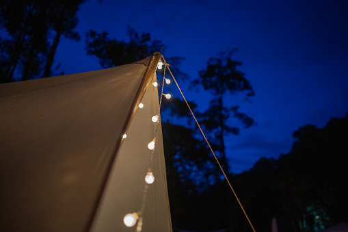 Night electric lamp hanging in camping tent light up at rainforest