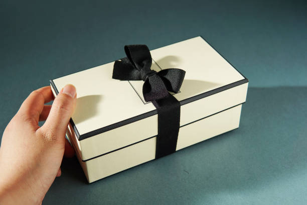 Hand holding a gift box against green background.
