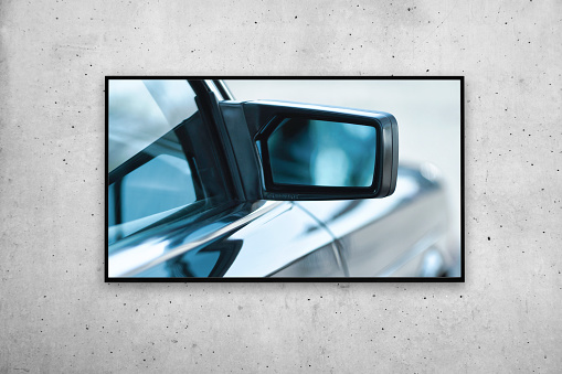 TV or picture frame on the gray concrete wall. it shows a historic car with a view of the outside mirror