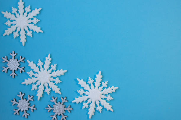 istock White and silvery snowflakes in shape frame on blue background for greeting card. 1439838236