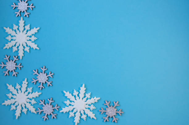 istock White and silvery snowflakes in shape frame on blue background for greeting card. 1439838237
