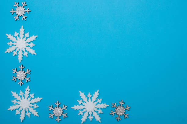 istock White and silvery snowflakes in shape frame on blue background for greeting card. 1439838258