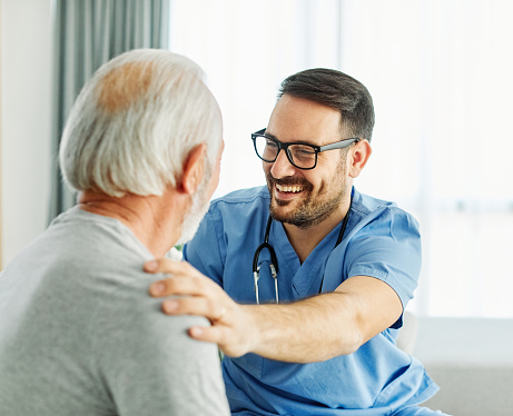 Portrait of a doctor or nurse caregiver supporting senior man, hand on the shoulder care and hug at home or nursing home