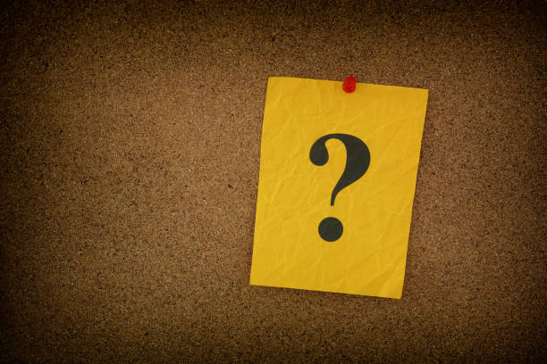 istock Yellow crumpled paper note with question marks on it pinned to a cork board 1439838800