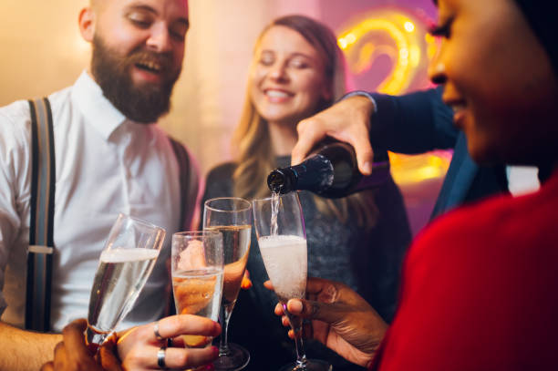 istock People hands holding flute glasses while pouring champagne 1439843512