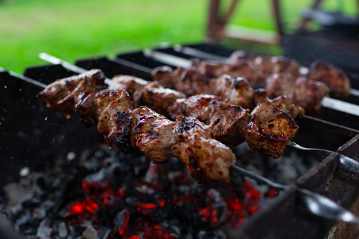 Close-up of skewered meat (shashlyk or Shish kebab) on the barbecue grill over charcoal