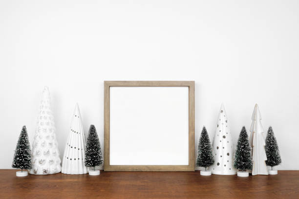 istock Christmas mock up with wooden frame and tree decor on a white shelf against a white wall 1439845011