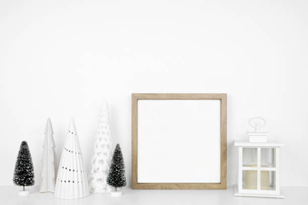 istock Christmas mock up with wooden frame, lantern and tree decor on a white shelf against a white wall 1439845070