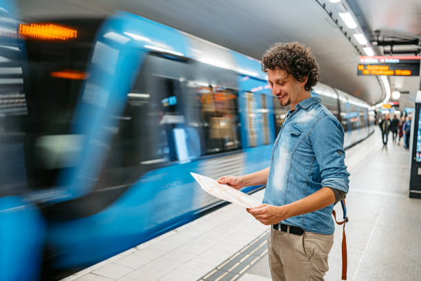 giovane turista maschio che legge una mappa mentre aspetta un treno della metropolitana a stoccolma - treno pendolare foto e immagini stock