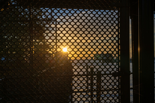 A sunset viewed through a chain link fence on the Seattle waterfront.