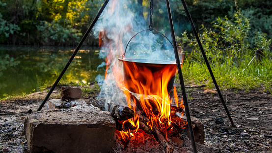 Cooking on a campfire in nature, cooking on a campfire in the campaign. Camp kitchen, cooking in the forest on a fire. Pot on an open fire. The concept of camping life.