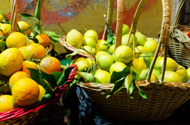 Large Italian lemons and oranges with green leaves in a basket. Many fresh vegetables and fruits are sold in street stalls on the streets of Naples, Italy. Horizontal orientation. stock photo