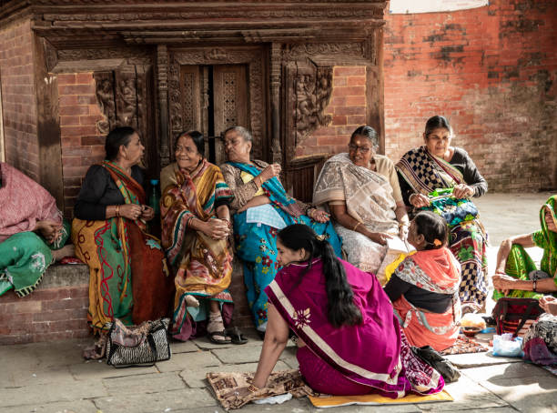 Kathmandu, Nepal - nov 6, 2019: a group of Nepalese women in traditional clothes chat sitting near a small temple in Durbar Square in Kathmandu