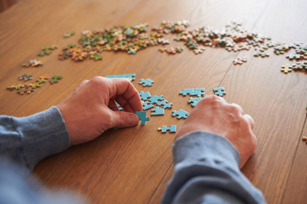 istock Unidentifiable male working on a jigsaw on a dining room table 1439861336