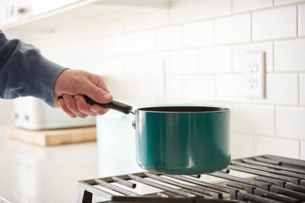 istock Unidentifiable middle aged man at gas stove in a modern bright white kitchen 1439861357