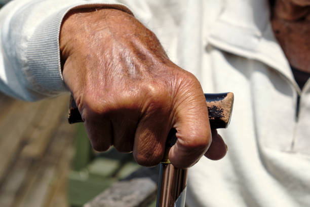 杖を持つ浅黒い肌の年配の男性の接写。 - human hand aging process senior adult cane ストックフォトと画像