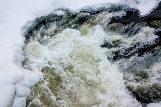 A winter aerial view of a river and its freezing flowing waters