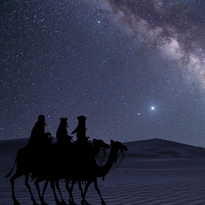 Three wise men traveling in the darkness of the desert, guided by the stars. Silhouettes.